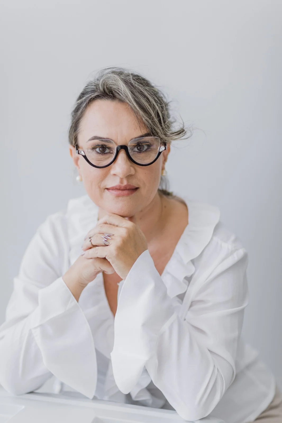 Retrato profissional da Dra. Cristina de Checchi, usando óculos e camisa branca